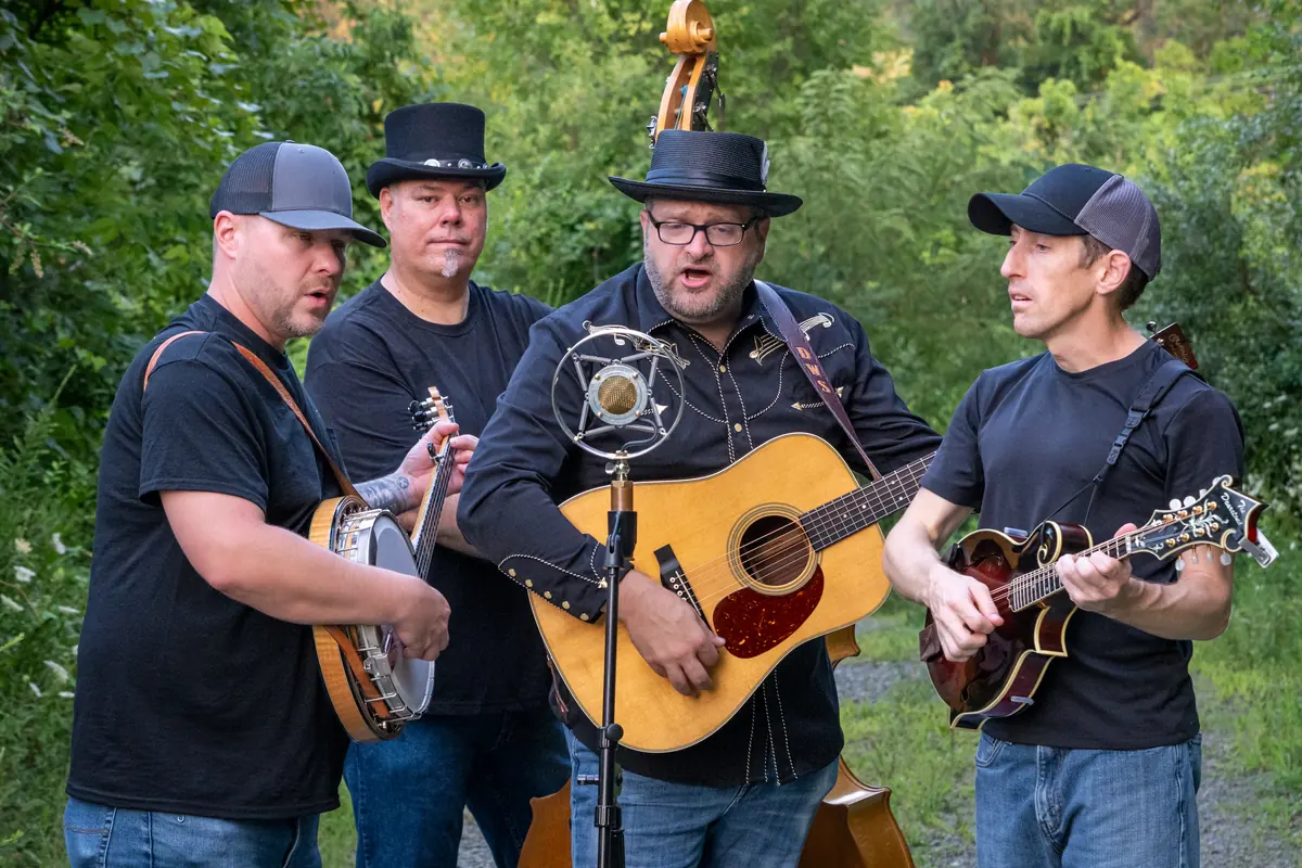 David Wade & Black Mountain gathered around a vintage microphone while singing and playing bluegrass