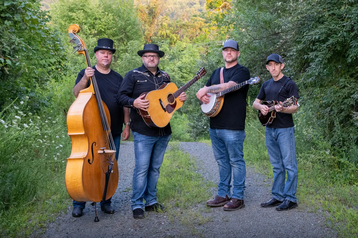 David Wade & Black Mountain standing with guitar, bass, banjo, and mandolin on a wooded Virginia trail