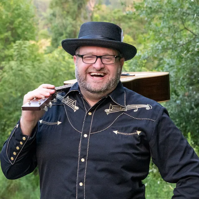 David Wade smiling with a guitar resting over his shoulder
