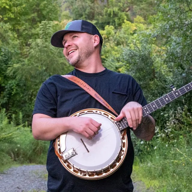 Jered Gillispie laughing while holding his banjo